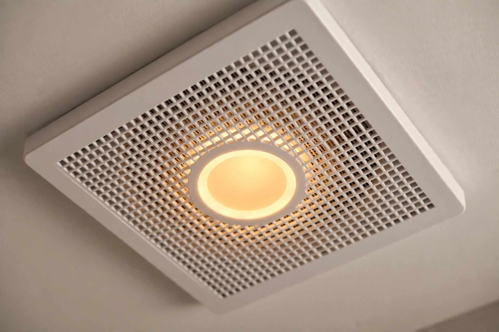 New bathroom exhaust fan with light installed in a tiled bathroom ceiling